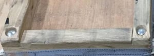 Close-up photo of a wooden piano moving board, showing the corner construction with bolts and fabric straps.
