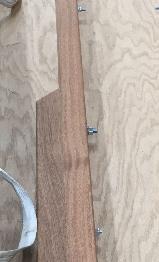 Side view photo of a wooden piano moving board, displaying the bolts and fabric strap attachments along its length.