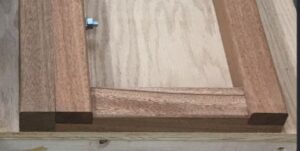 Close-up photo of a wooden piano moving board, showing detailed joinery and a bolt for securing the board.