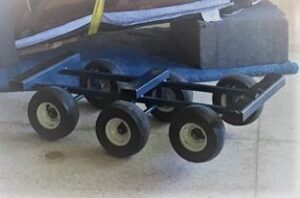 Photo of a small, multi-wheeled piano dolly used for moving heavy items. The dolly is shown on a tiled floor, partially underneath a padded item.